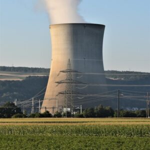 a power plant emits smoke as it sits in the middle of a field